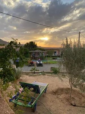 a bench in a yard with the sunset in the background at Les cavaliers chez Yassine in Marrakech