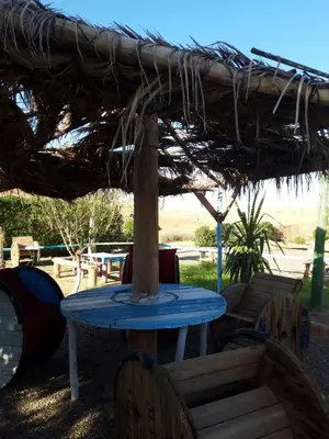 a blue table and chairs under a straw umbrella at Les cavaliers chez Yassine in Marrakech