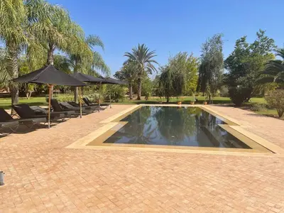 a swimming pool with chairs and umbrellas in a park at Maidan El Arsa in Marrakech