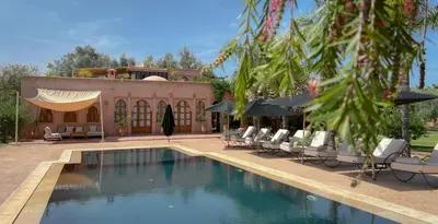 a swimming pool with chairs and umbrellas next to a house at Maidan El Arsa in Marrakech