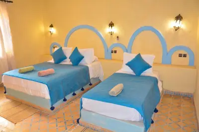two beds in a room with blue and white at Sahara House in Merzouga