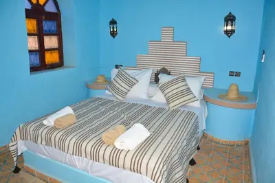 a bed in a blue room with towels on it at Sahara House in Merzouga