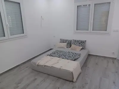 a bed in a white room with two windows at Maison familiale avec piscine privée sans vis à vis in Tarhia
