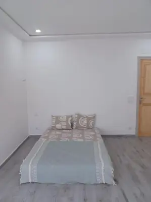 a large bed in a white room with a wooden floor at Maison familiale avec piscine privée sans vis à vis in Tarhia