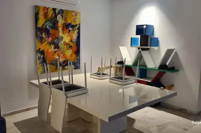 a room with a table and some paintings on a wall at Appartement spacieux et luxueux in Fès
