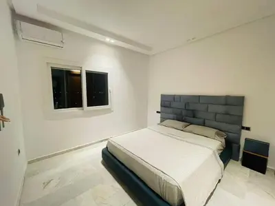 a white bedroom with a bed and a window at Appartement spacieux et luxueux in Fès