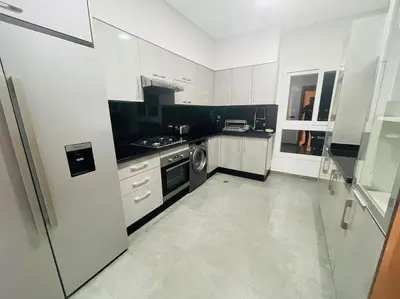 a white kitchen with a stove and a dishwasher at Appartement spacieux et luxueux in Fès