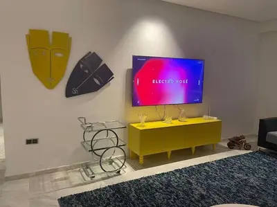 a living room with a tv and a yellow table at Appartement spacieux et luxueux in Fès