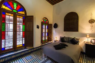 a bedroom with a bed and stained glass windows at Dar Nejma in Fès