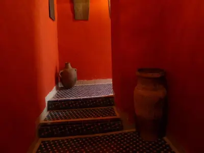 a red hallway with two steps and a vase at Dar Nejma in Fès