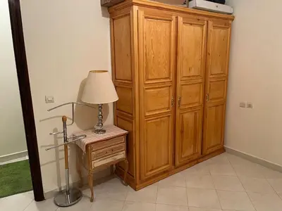 a large wooden cabinet next to a table with a lamp at Meknes Apartment Oudi in Meknès