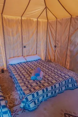 a bed in a tent with a towel on it at Silent Camp in Mhamid
