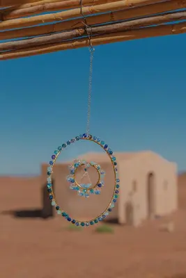 a circle of beads hanging on a pole in the desert at Silent Camp in Mhamid