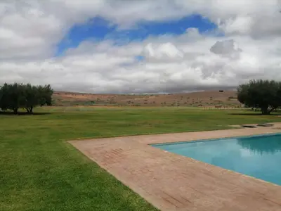 a swimming pool in the middle of a field at Domaine Lamrah in Marrakech