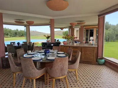 a dining room with a table and chairs and a kitchen at Domaine Lamrah in Marrakech