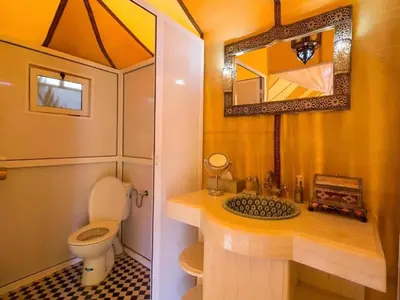 a small bathroom with a toilet and a mirror at Sahara Family Luxury Camp in Merzouga