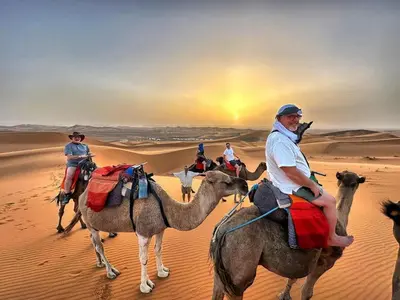 a group of people riding on camels in the desert at Sahara Family Luxury Camp in Merzouga