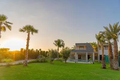 a house with palm trees in front of a yard at Villa Marrakech vue atlas in Marrakech