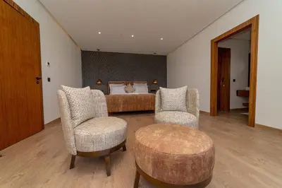 a bedroom with a bed and two chairs and a table at Villa Marrakech vue atlas in Marrakech
