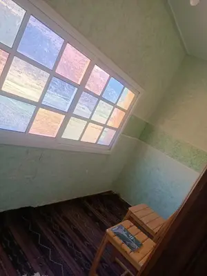 an attic room with a large window and a bed at Ait Ayoub Voyages in Azilal