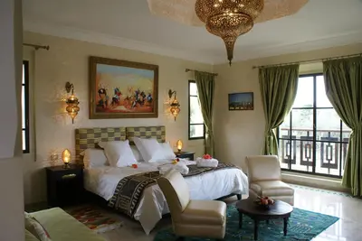 a bedroom with a large bed and a chandelier at La Kasbah Aalma D'or in Najem