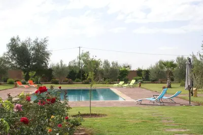 a yard with a swimming pool with two chairs and flowers at La Kasbah Aalma D'or in Najem
