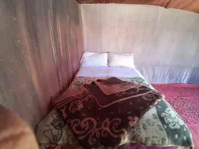a small bed in a small room with a bedspread at Unforgettable Nights in Merzouga in Merzouga
