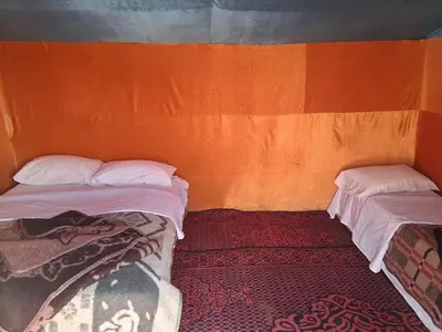 two beds in a room with an orange wall at Unforgettable Nights in Merzouga in Merzouga