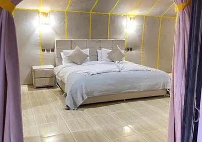 a bedroom with a large white bed with yellow stripes at Magnificent Luxury Camp in Merzouga