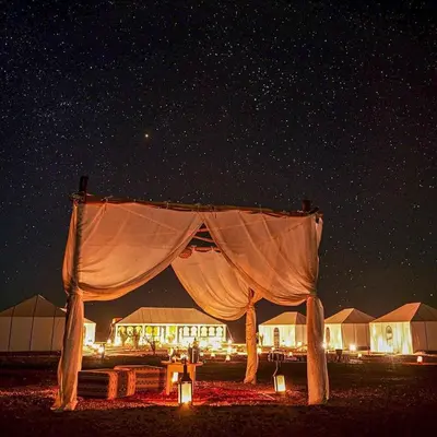 a tent set up in the desert at night at Magnificent Luxury Camp in Merzouga