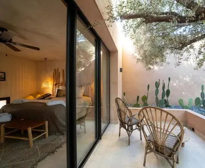 a bedroom with a bed and a table and chairs at Jardin Sakina - Séjour paisible avec soins bien-être, à 35 minutes de Marrakech in Marrakech