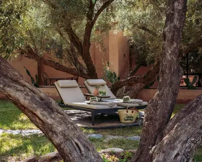 a chair and a table under some trees at Jardin Sakina - Séjour paisible avec soins bien-être, à 35 minutes de Marrakech in Marrakech