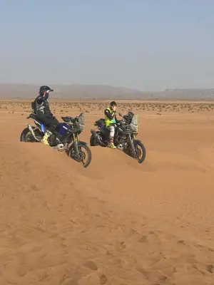 two people are riding motorcycles in the desert at Touareg Desert Camp Erg Chigaga in El Gouera