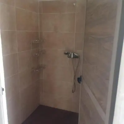 a bathroom with a shower with a glass door at Touareg Desert Camp Erg Chigaga in El Gouera