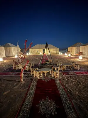 a group of tables and chairs in a field at night at Touareg Desert Camp Erg Chigaga in El Gouera