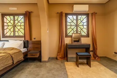 a bedroom with a bed and a desk and two windows at Villa a Marrakech with private pool in Marrakech