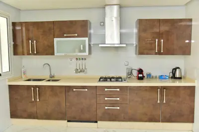 a kitchen with wooden cabinets and a sink at Luxueux Appartement Parc Champs de Cours avec Wifi Fibre 200 Mo in Fès
