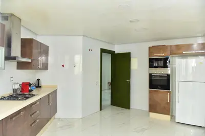 a kitchen with wooden cabinets and a green door at Luxueux Appartement Parc Champs de Cours avec Wifi Fibre 200 Mo in Fès