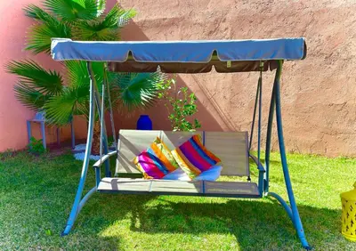 a swing with pillows on it in a yard at Niche paradis in Aghmat
