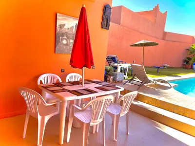 a dining room with a table and chairs and a pool at Niche paradis in Aghmat