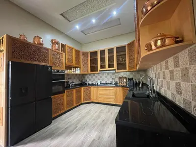 a kitchen with wooden cabinets and a black refrigerator at Riad Marjana in Marrakech