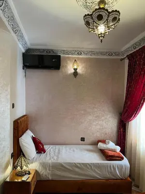 a bedroom with a bed with red pillows and a chandelier at Appartement Authentique à la Médina de Fès - À Deux Pas de Bab Bou Jeloud & des Souks in Fès al Bali