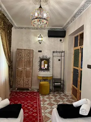a room with two beds and a mirror and a chandelier at Appartement Authentique à la Médina de Fès - À Deux Pas de Bab Bou Jeloud & des Souks in Fès al Bali
