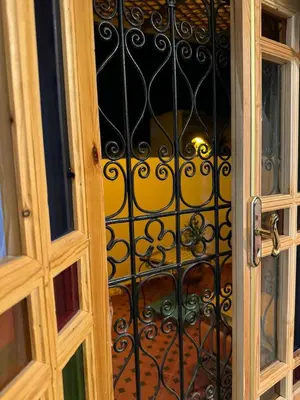 a door with a iron gate with a glass window at Appart Sahraoui Medina in Fès al Bali