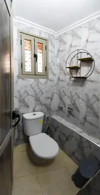 a bathroom with a white toilet and marble walls at Appart Sahraoui Medina in Fès al Bali