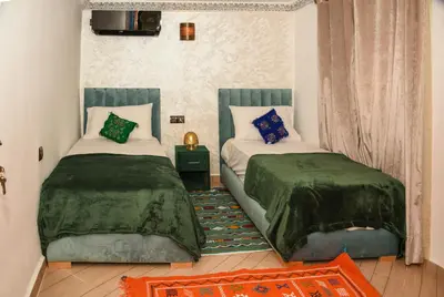 a bedroom with two beds with green comforters at Appart Sahraoui Medina in Fès al Bali