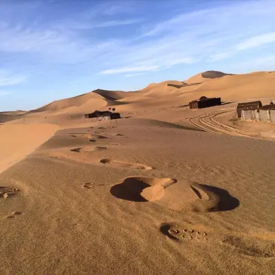 a desert with houses and footprints in the sand at Dar Sidi Bounou in Mhamid