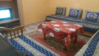 a room with two beds with a table and a tv at Bassatine appartement in Meknès