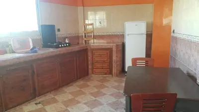 a kitchen with wooden cabinets and a white refrigerator at Bassatine appartement in Meknès
