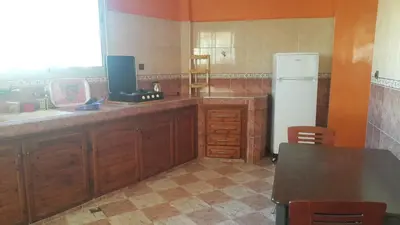 a kitchen with wooden cabinets and a white refrigerator at Bassatine appartement in Meknès